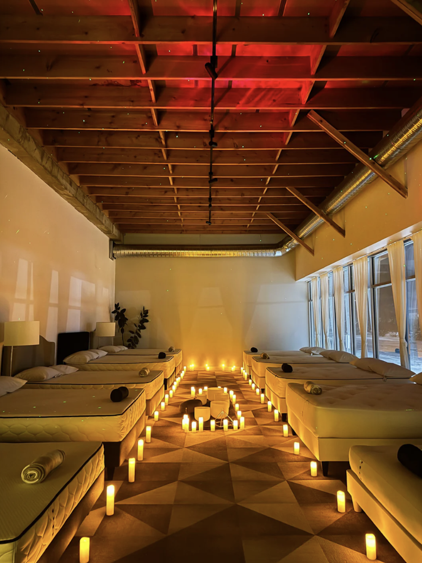 A mattress showroom with beds lining the walls and candles on the ground around the mattresses.