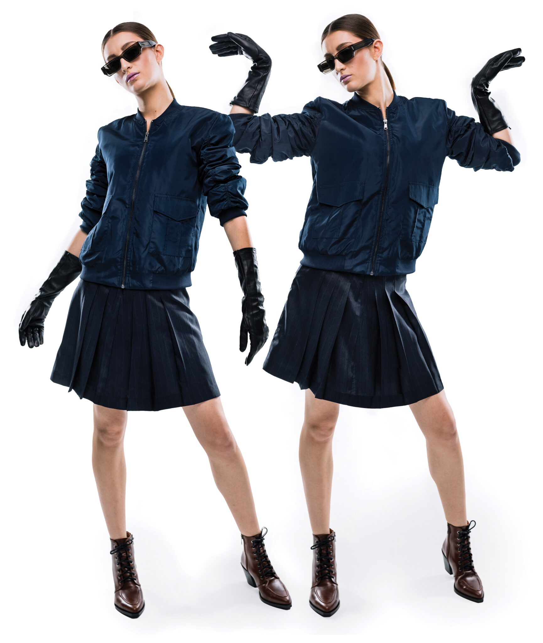 A model mirrored wearing a jacket, skirt, boots, gloves and sunglasses.