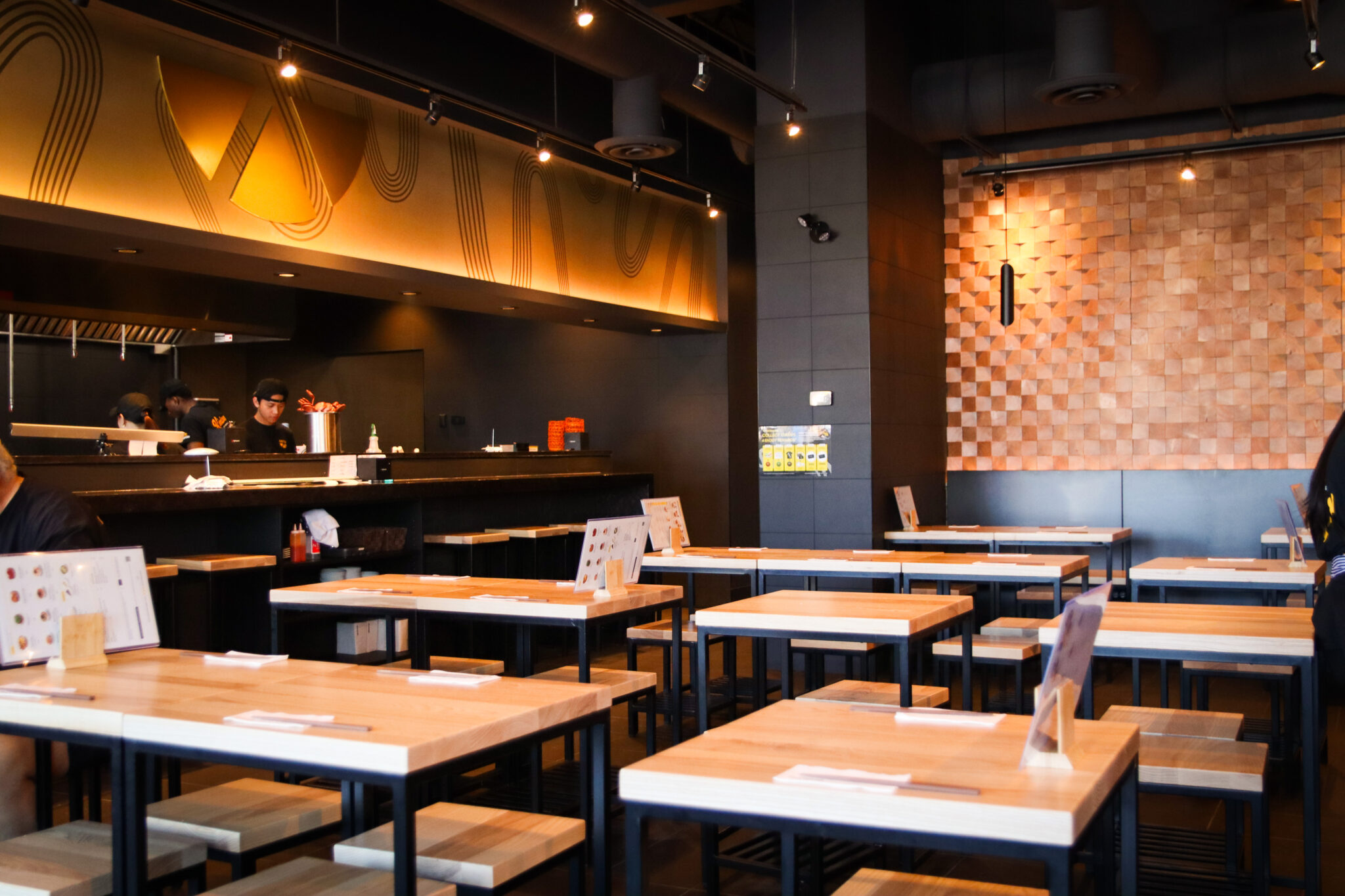 The kitchen overlooks the tables and chairs in Kinton Ramen's Calgary dining room.