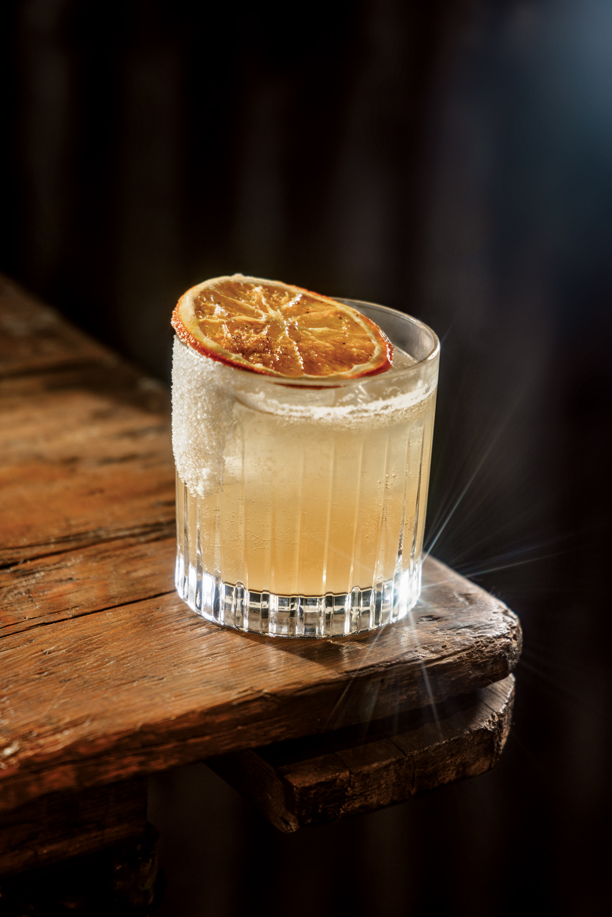 A glass with a non-alcoholic beverage with a salted rim and freeze-dried citrus.
