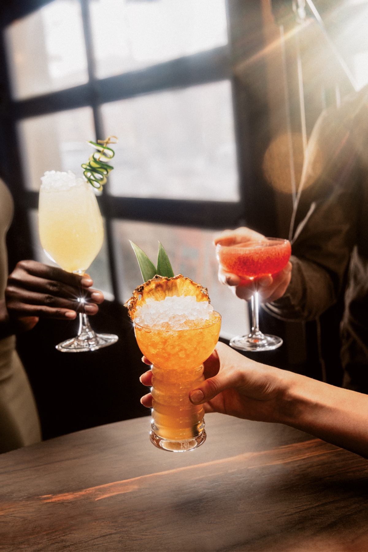 Three hands holding mocktails.