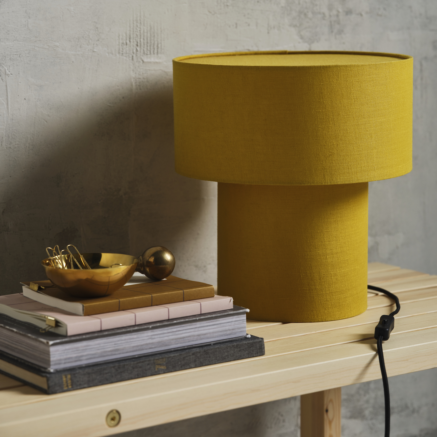 A yellow lamp sitting on a bench with a stack of books beside it