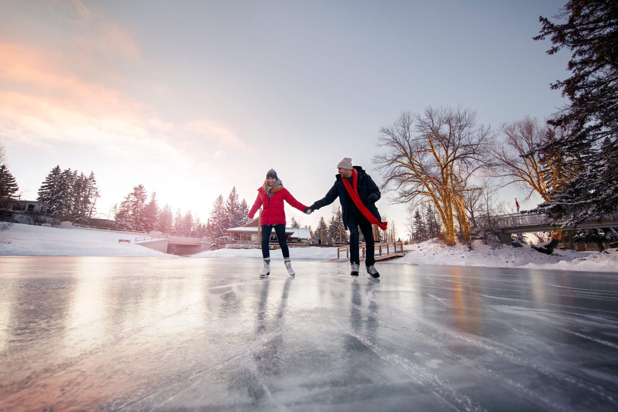 Two people hold hands and skate.