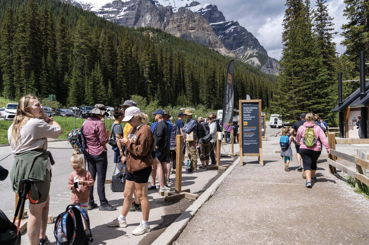 A long line of people waits to board a shuttle bus in Banff. 