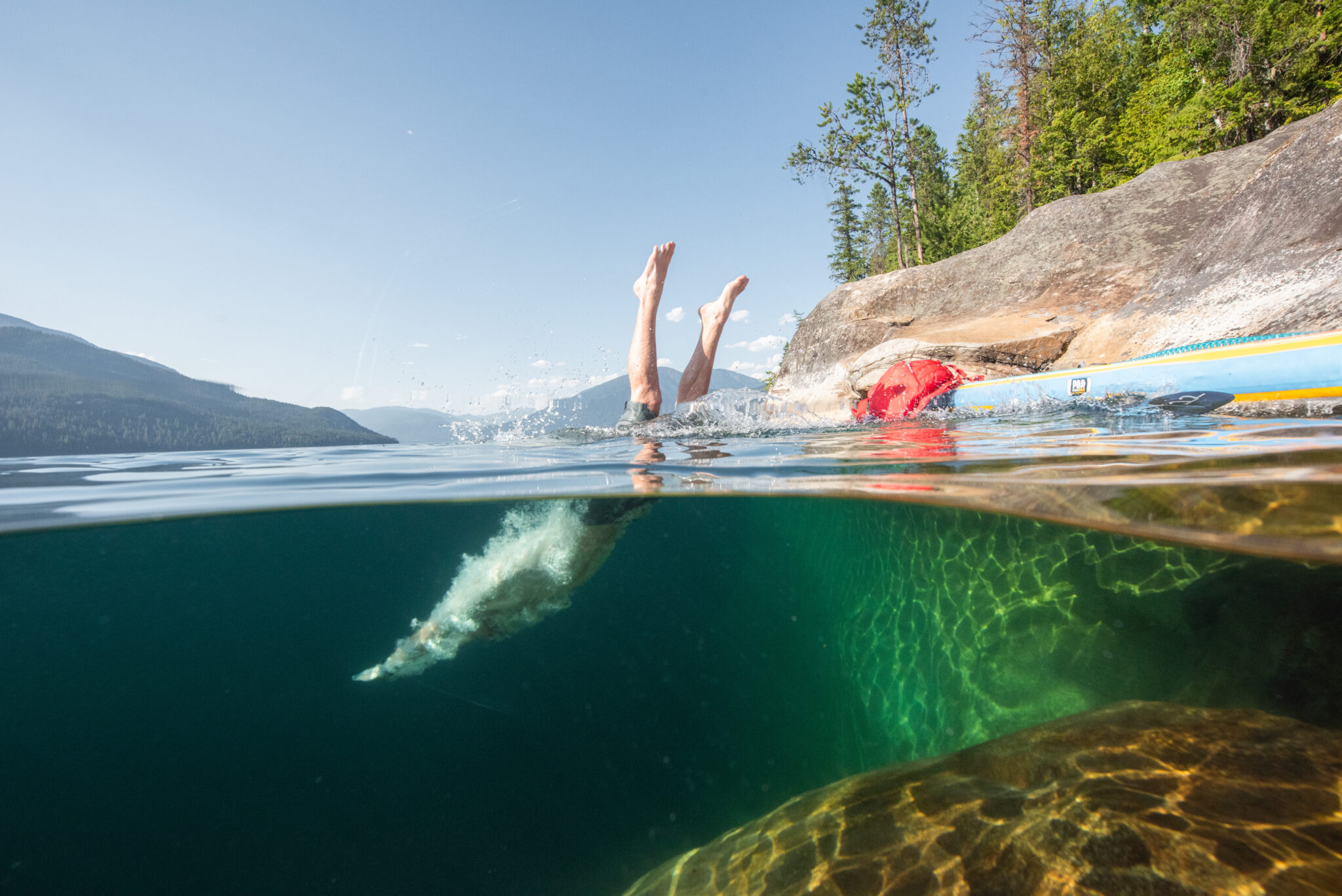 A swimmer dives into water in the mountains.