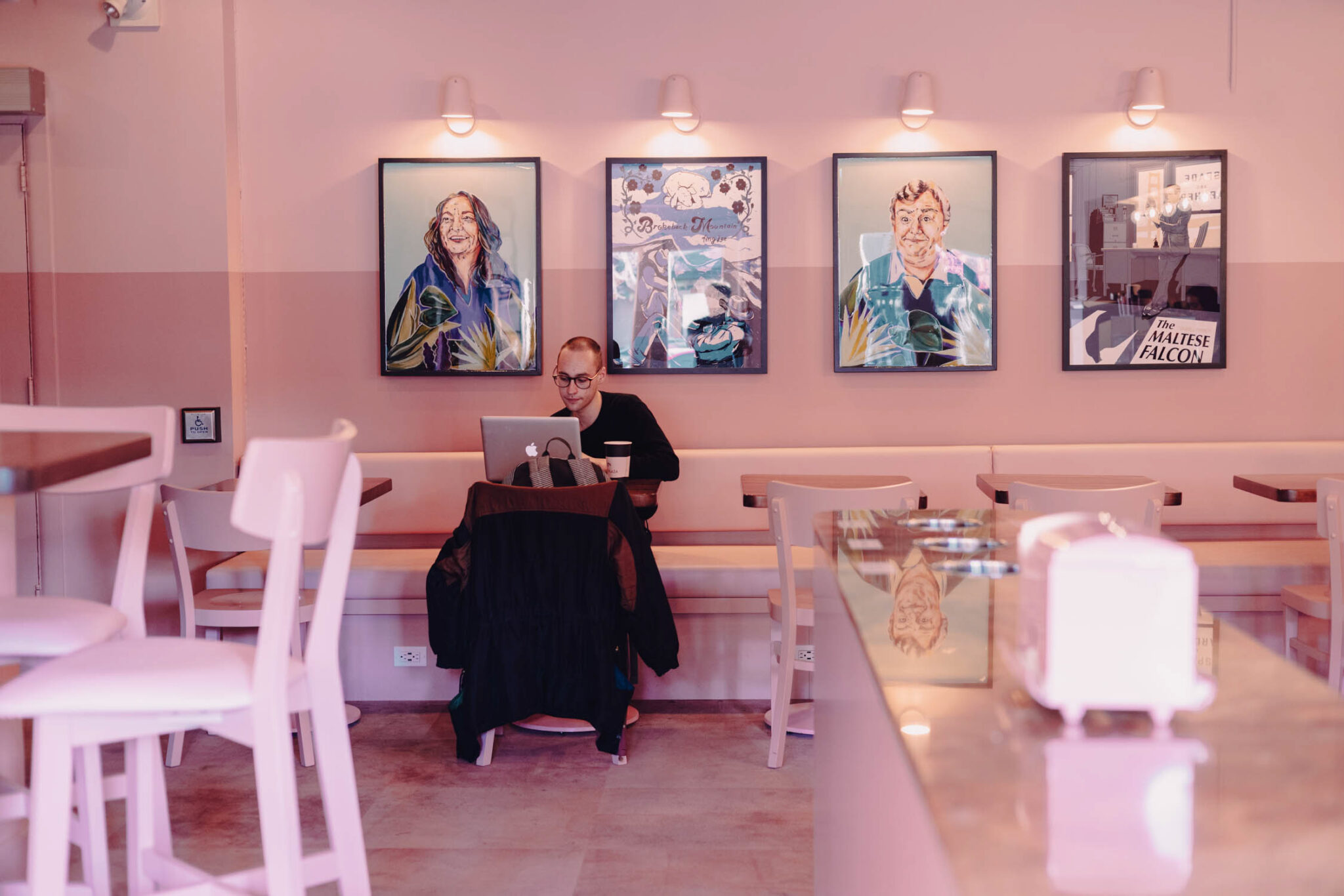 A man works on his computer in Plaza Theatre's pink lobby.