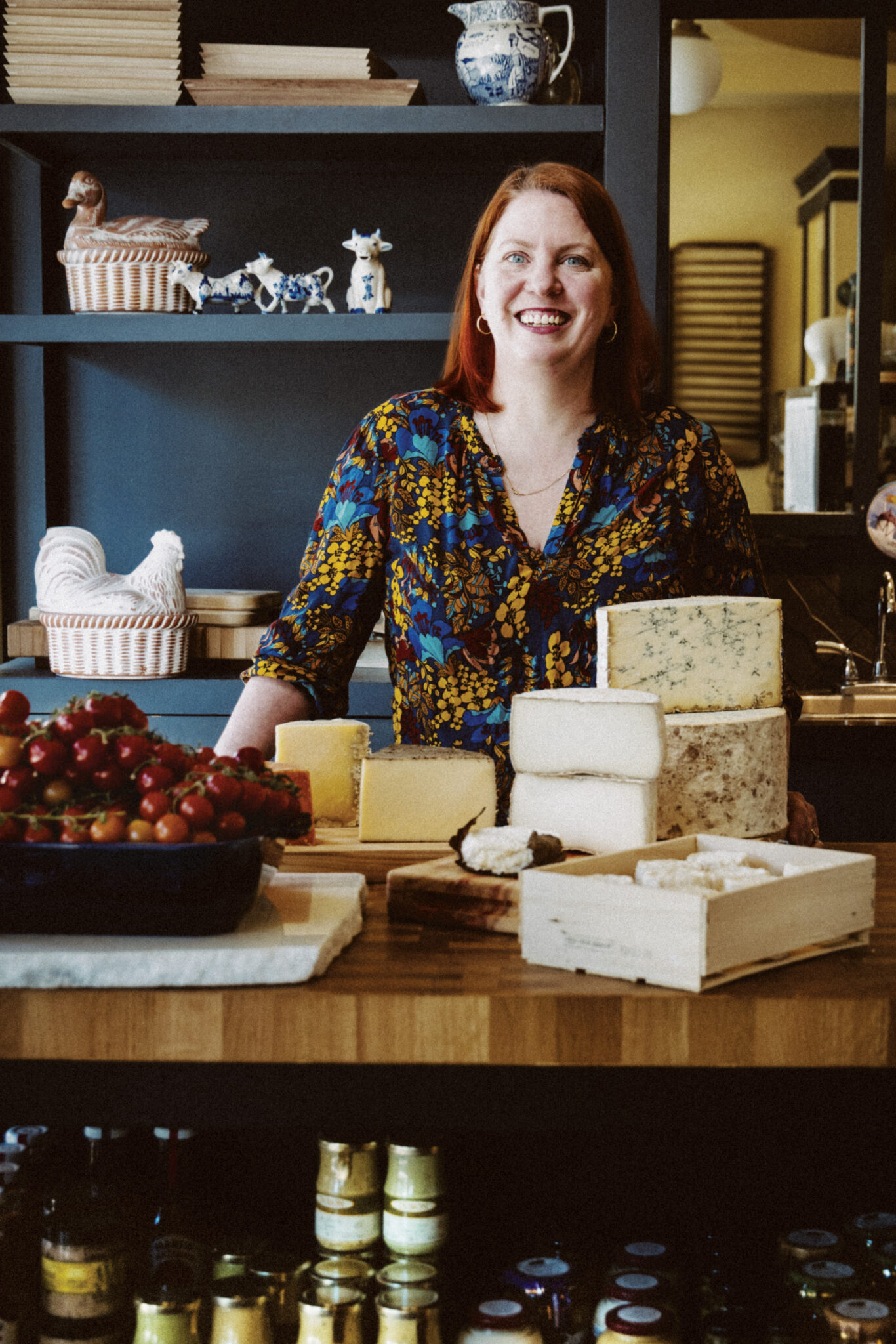 Peasant Cheese owner Crystal McKenzie stands behind an array of cheese blocks.