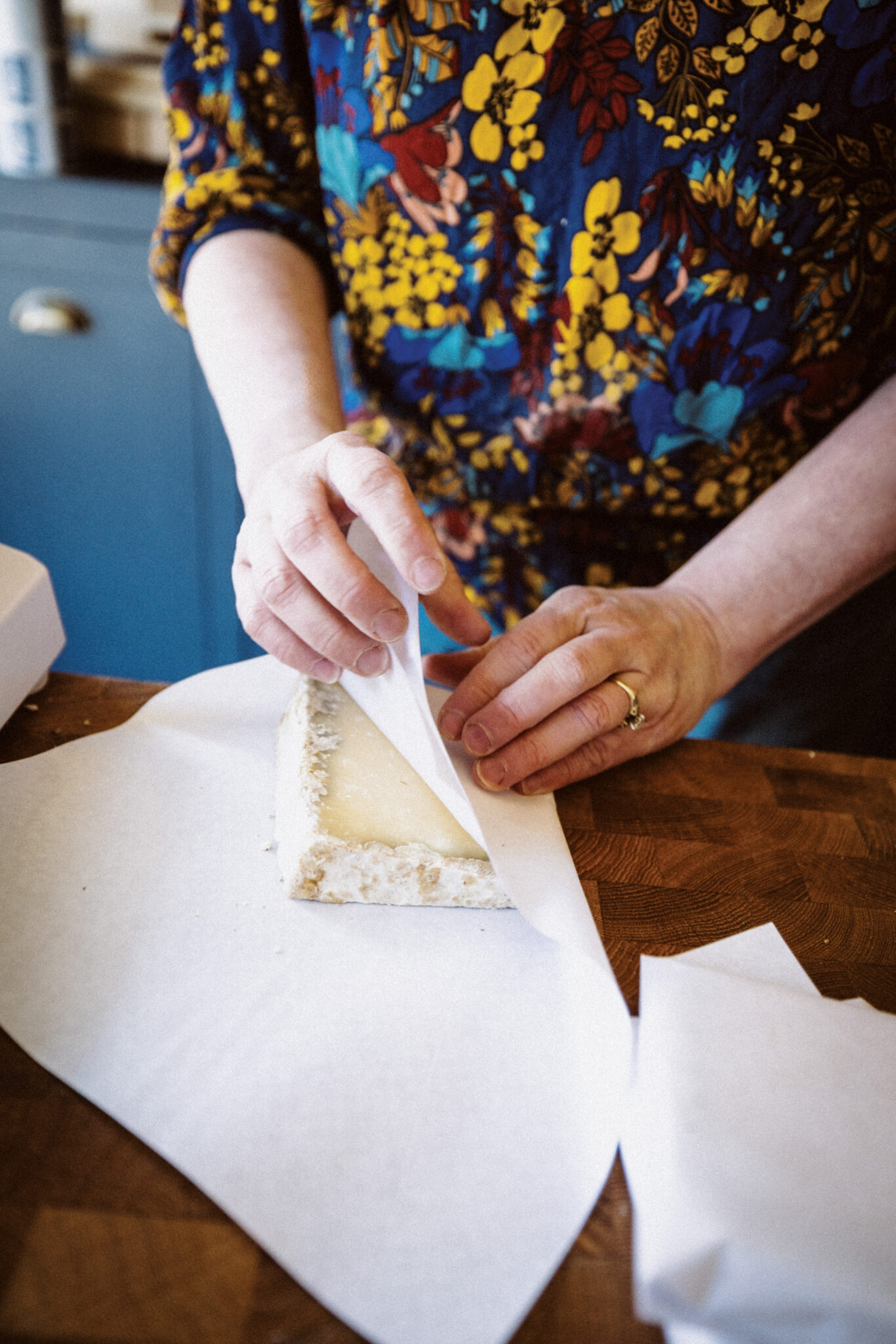 Hands wrapping a piece of cheese.