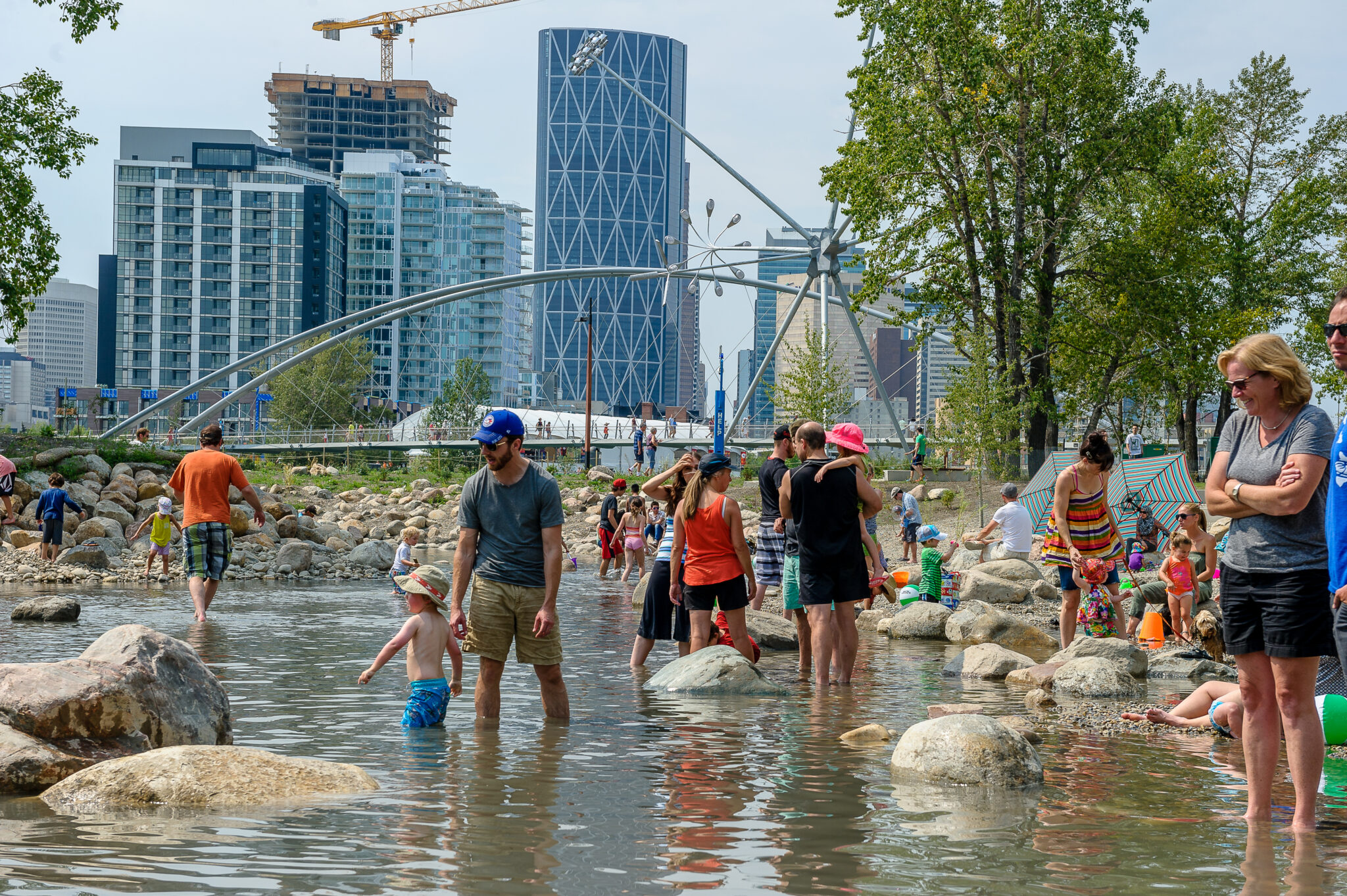 Families wade in the water with the Calgary skyline in the background.