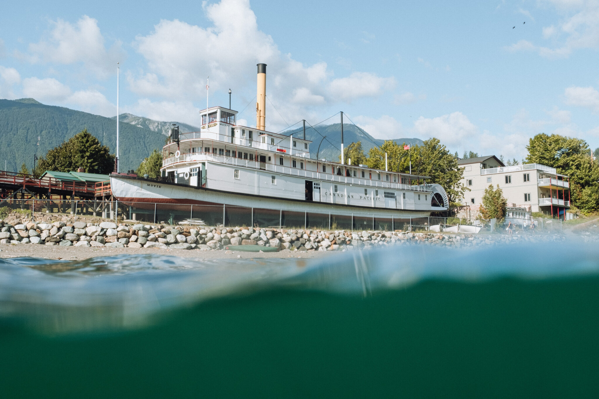 A boat sits on the shore near the water in the mountains.