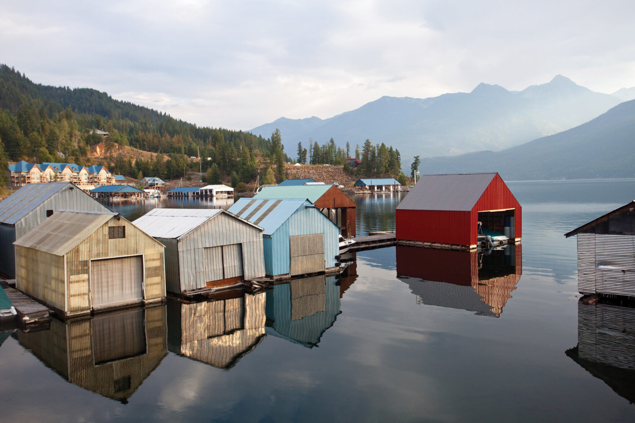Small houses sit upon a lake with a mountain in the background.