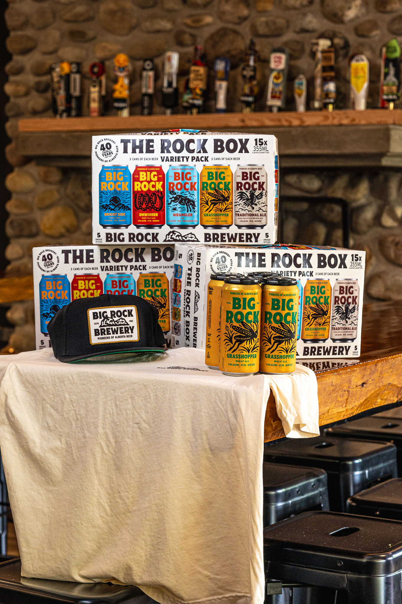 A table with boxes of Big Rock brewery beer, a four-pack of beer and a Big Rock hat.