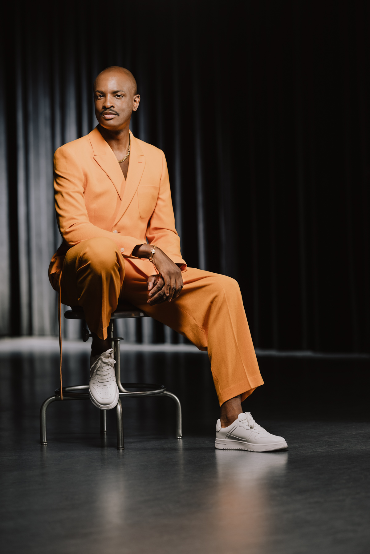 Justin Mulrain wears an orange suit with a pair of white shoes.