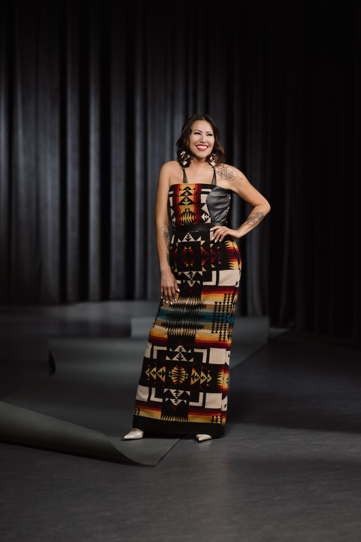 Stephanie Gamble wears earrings, heels and a long, colourful strapless dress.