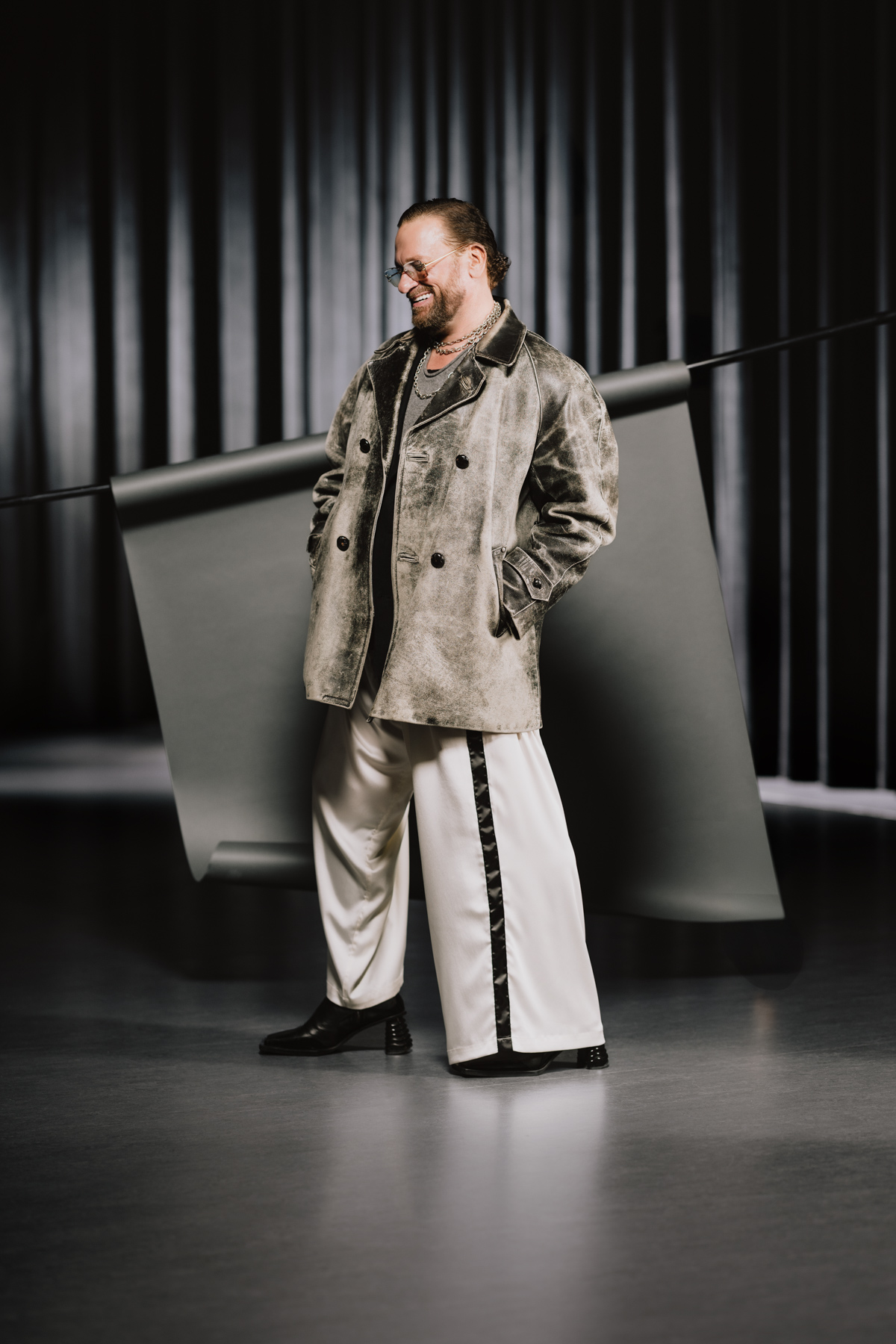 Kelly Streit wearing sunglasses, a grey jacket, wide-leg pants and black heeled boots.