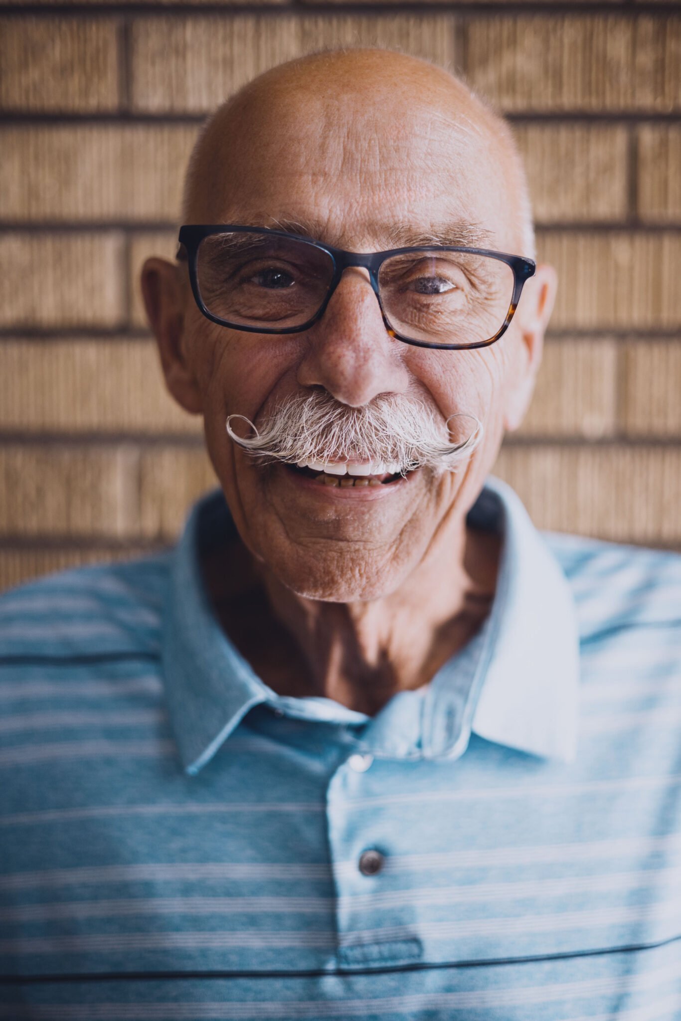 A man with glasses, a moustache and a blue shirt.