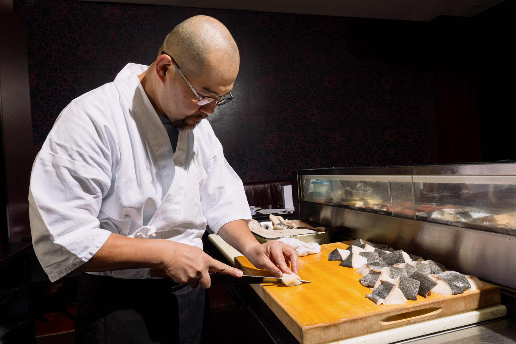 A chef cuts fish on a cutting board.