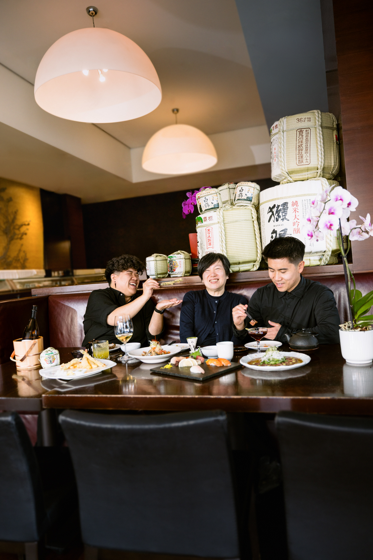 A family sits at a restaurant table and interacts with food in front of them.