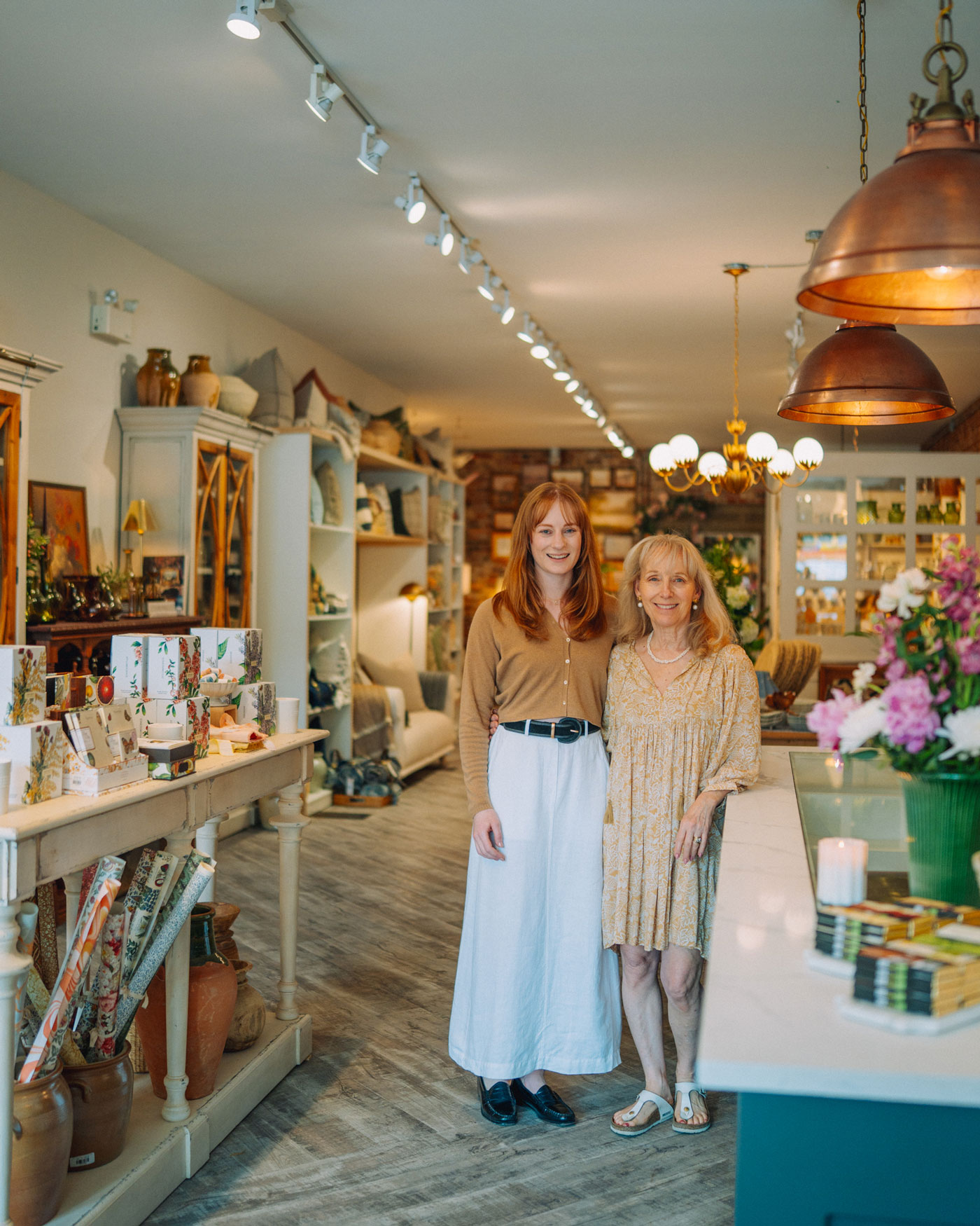 Two women stand in a store filled with home goods and lifestyle products.