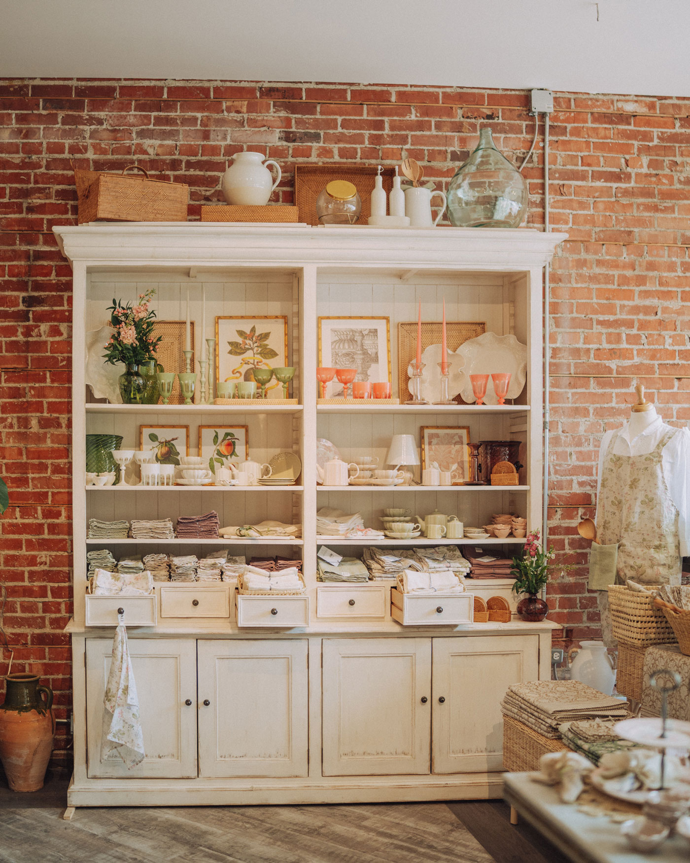 A cabinet against a brick wall displays home goods and other store products.