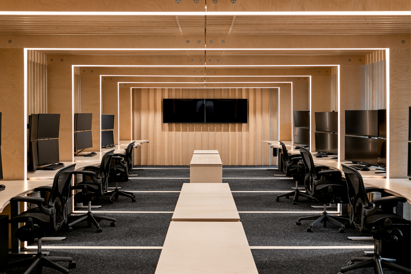 An office room with office chairs, desks and computers along the wall.