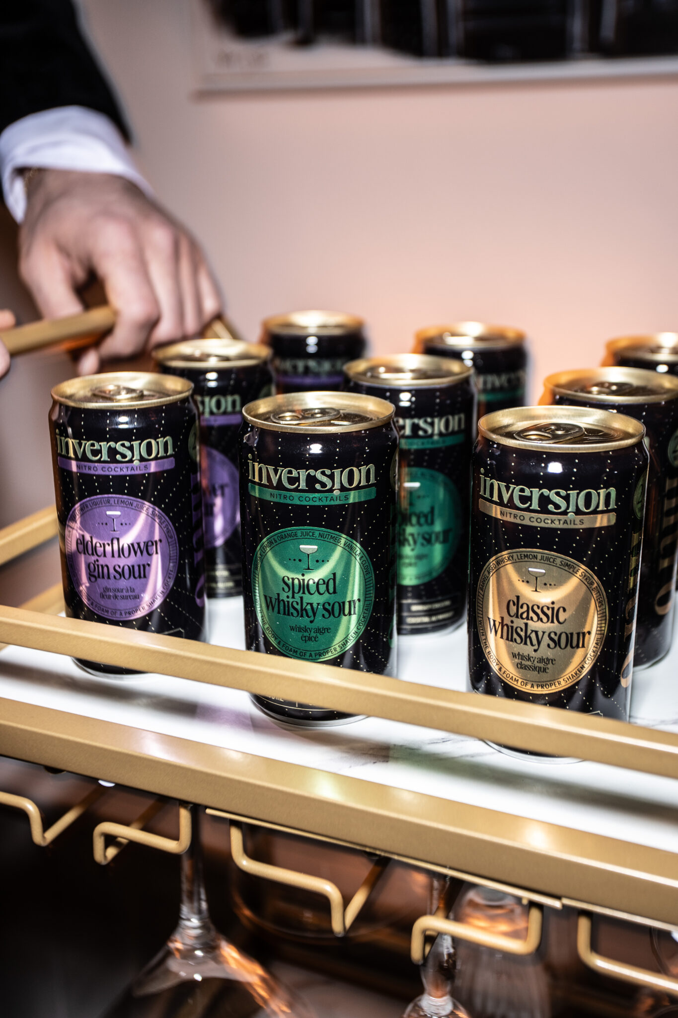 A hand pushes a bar cart with canned alcoholic beverages.