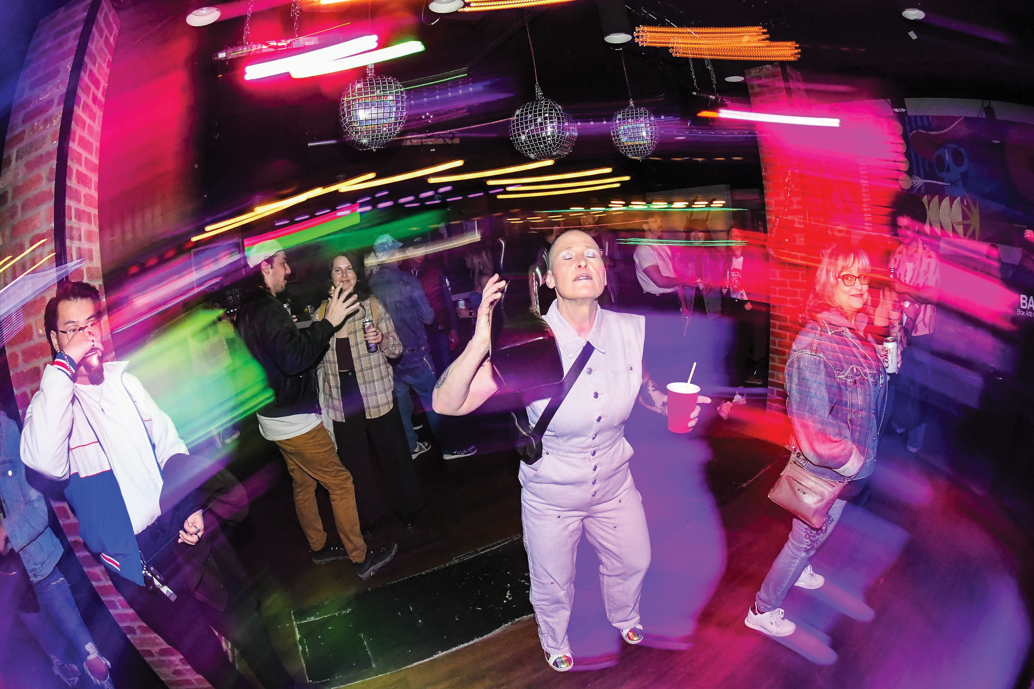 A blurry image of people standing under disco balls at an event.