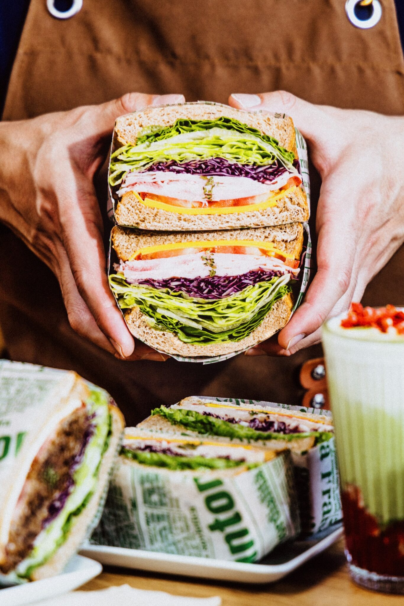 Two hands hold a cut sandwich that is full of colourful fillings