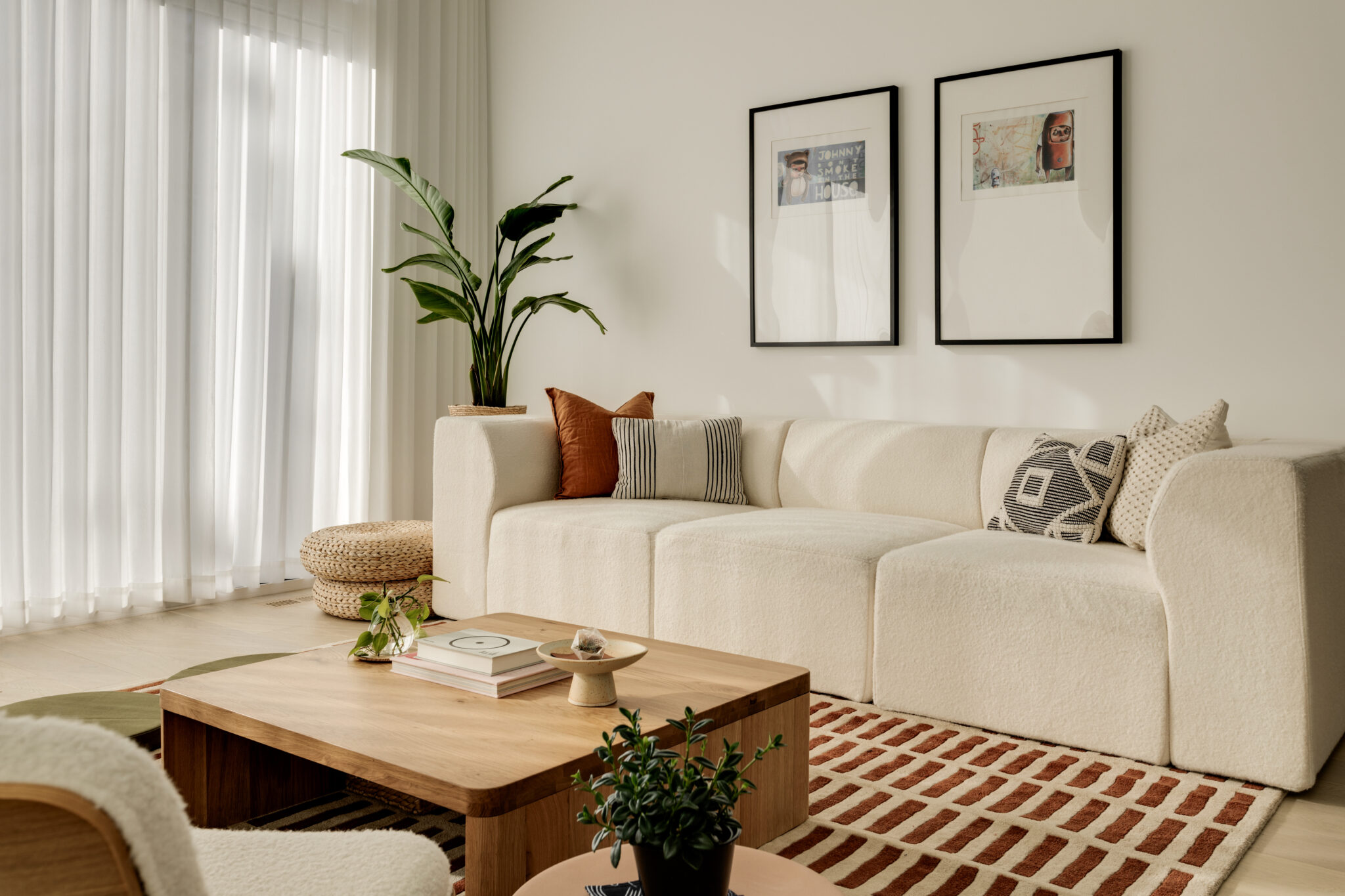 A living room with a white couch, a wooden coffee table and a colourful carpet.