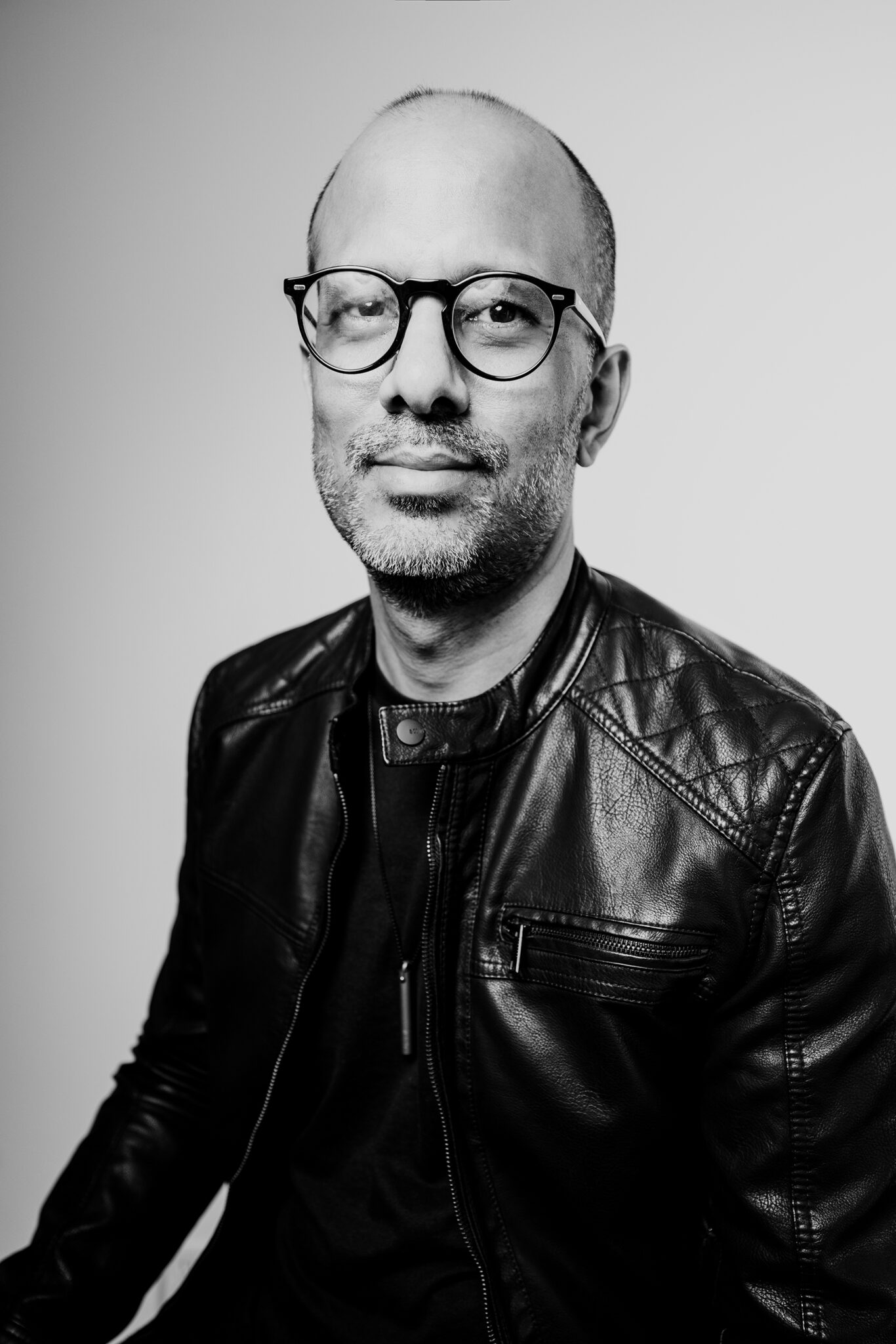 A black and white portrait of man wearing circular glasses.