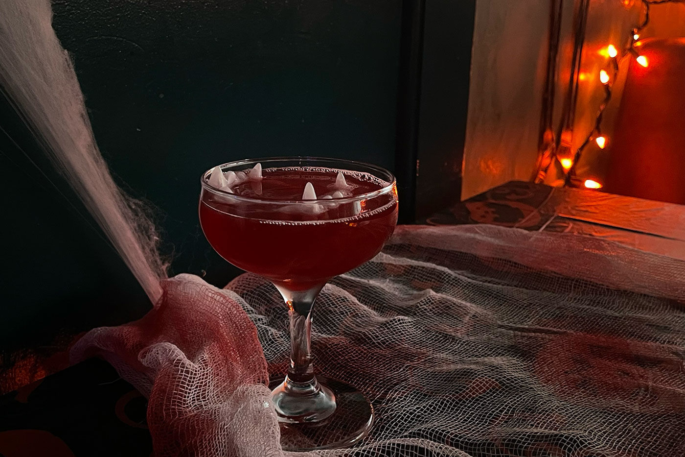 A red Halloween-themed cocktail with fake fangs floating in it