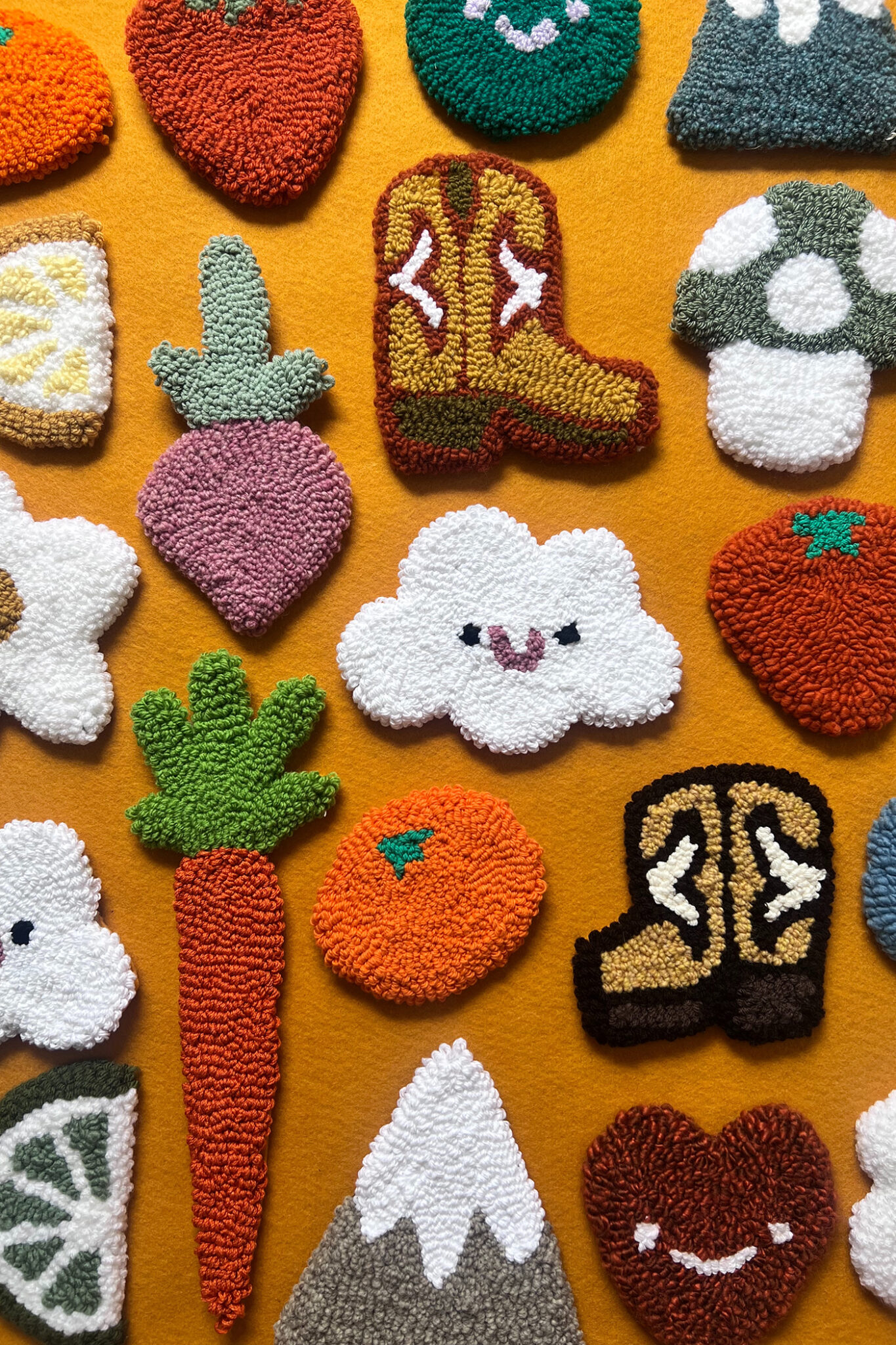 Tufted wall hangings in shapes like a carrot, cowboy boots, oranges and clouds.