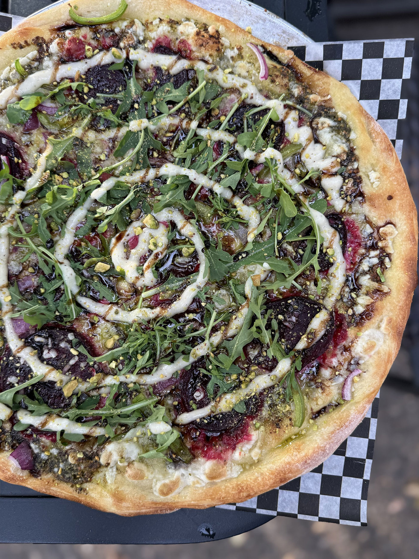 A pizza with sauce drizzled in a spiral pattern