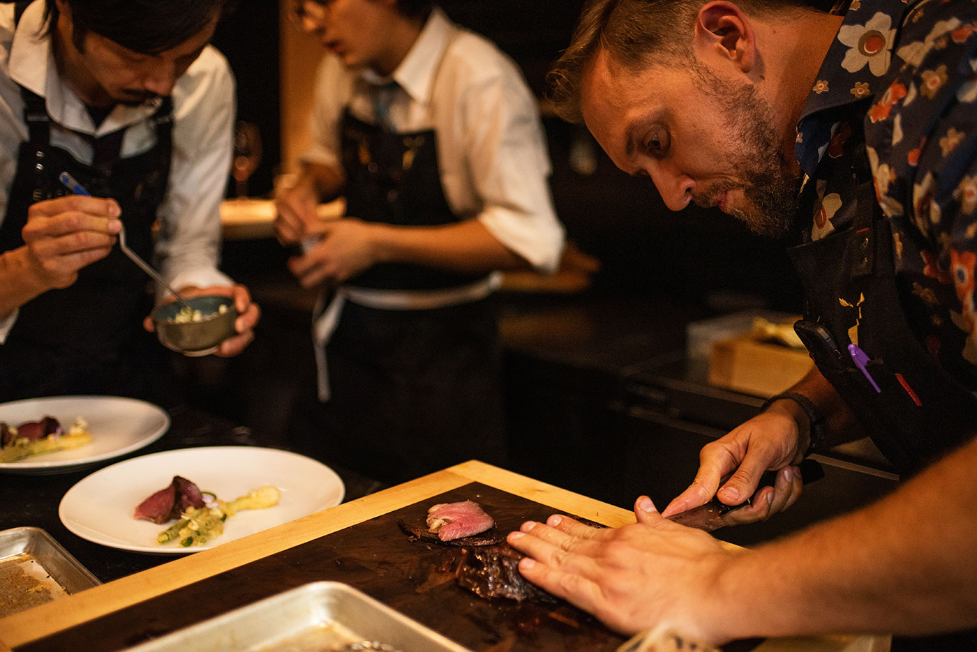 Chefs slice meat and prepare dishes at a restaurant