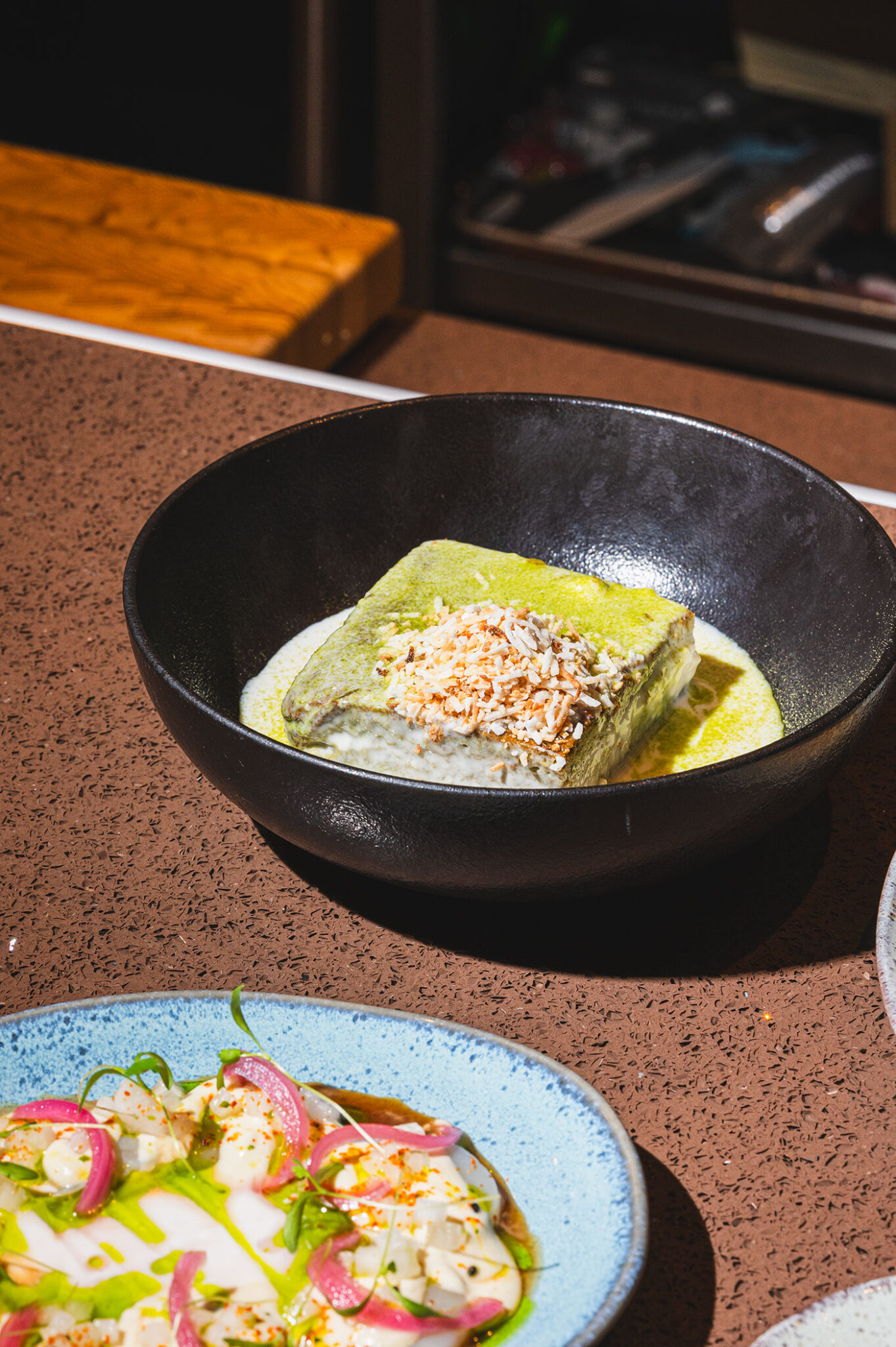A matcha cake soaked in milk sits in a bowl.