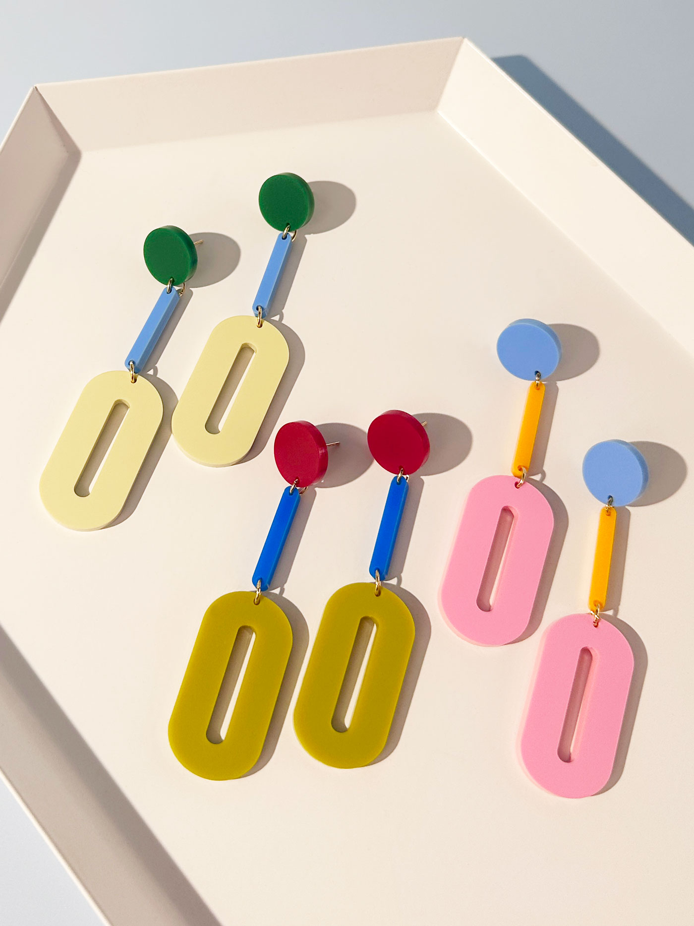 Three sets of colourful earrings on a platter