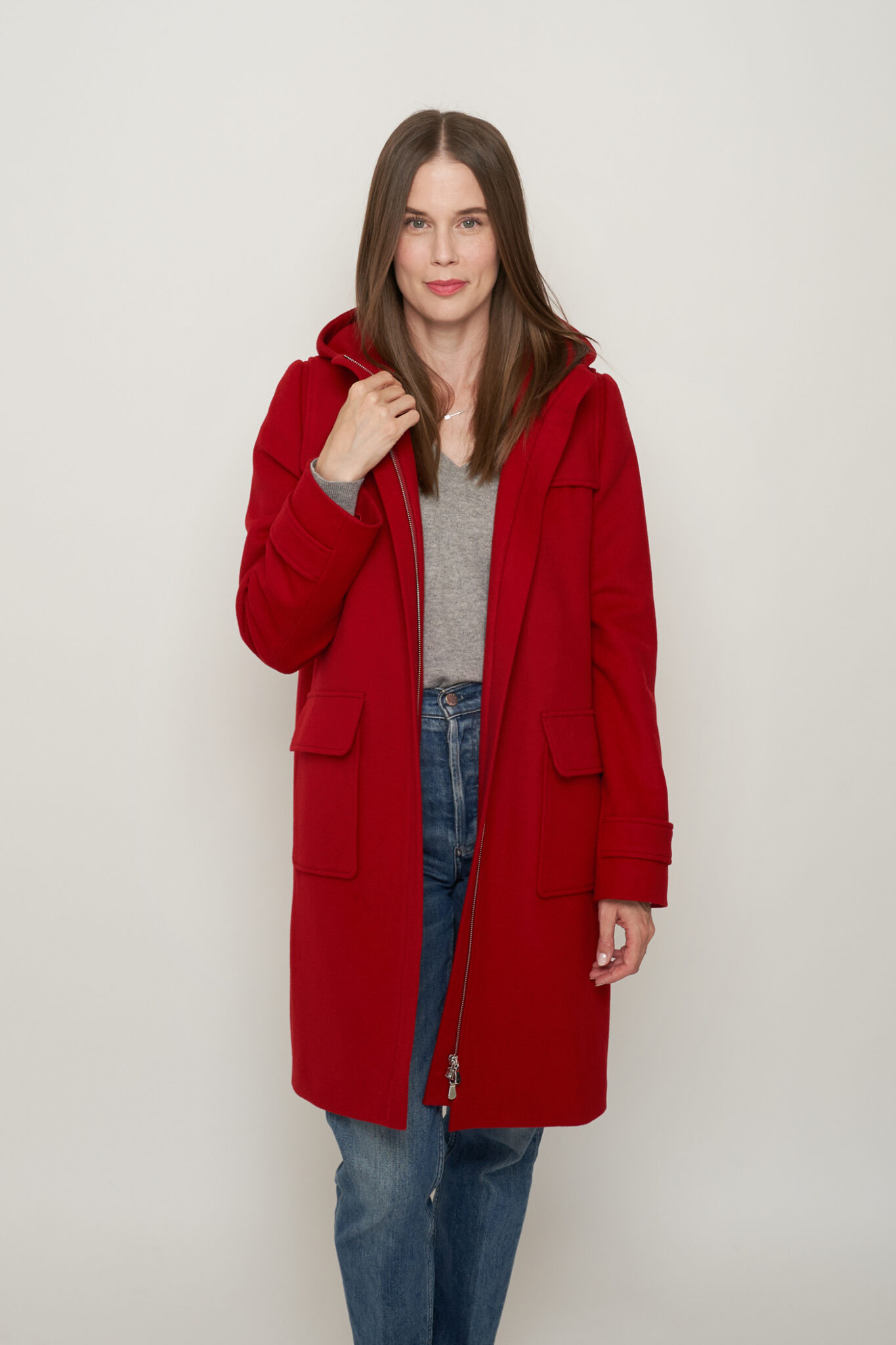 A woman with brown hair wears a red jacket with jeans