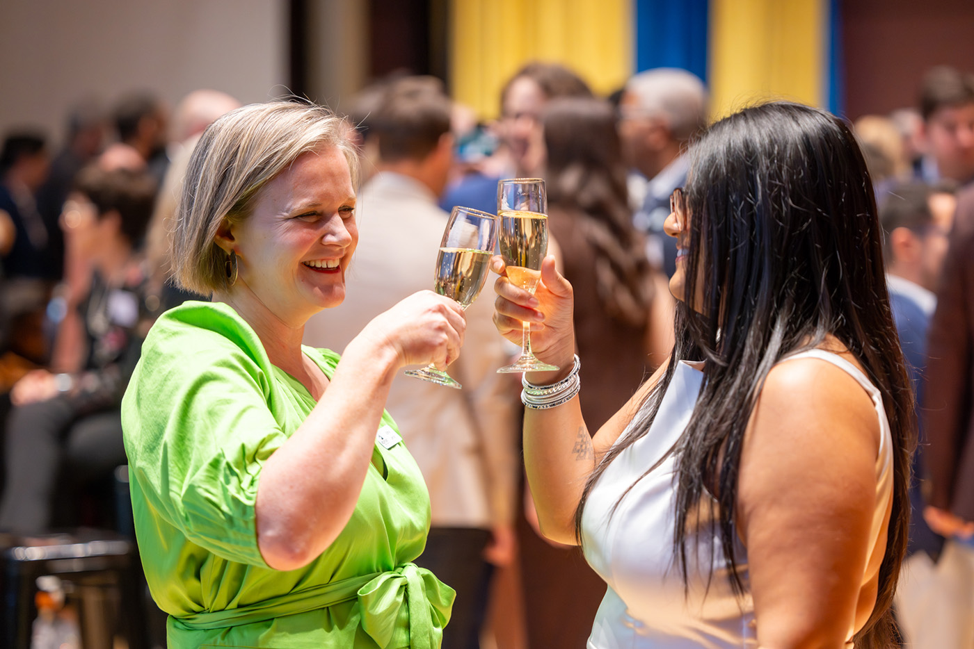 Two people cheers their drinks at an event