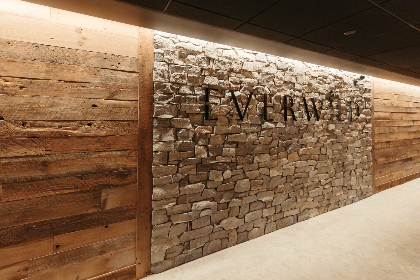 A wood and stone wall with the words Everwild on it