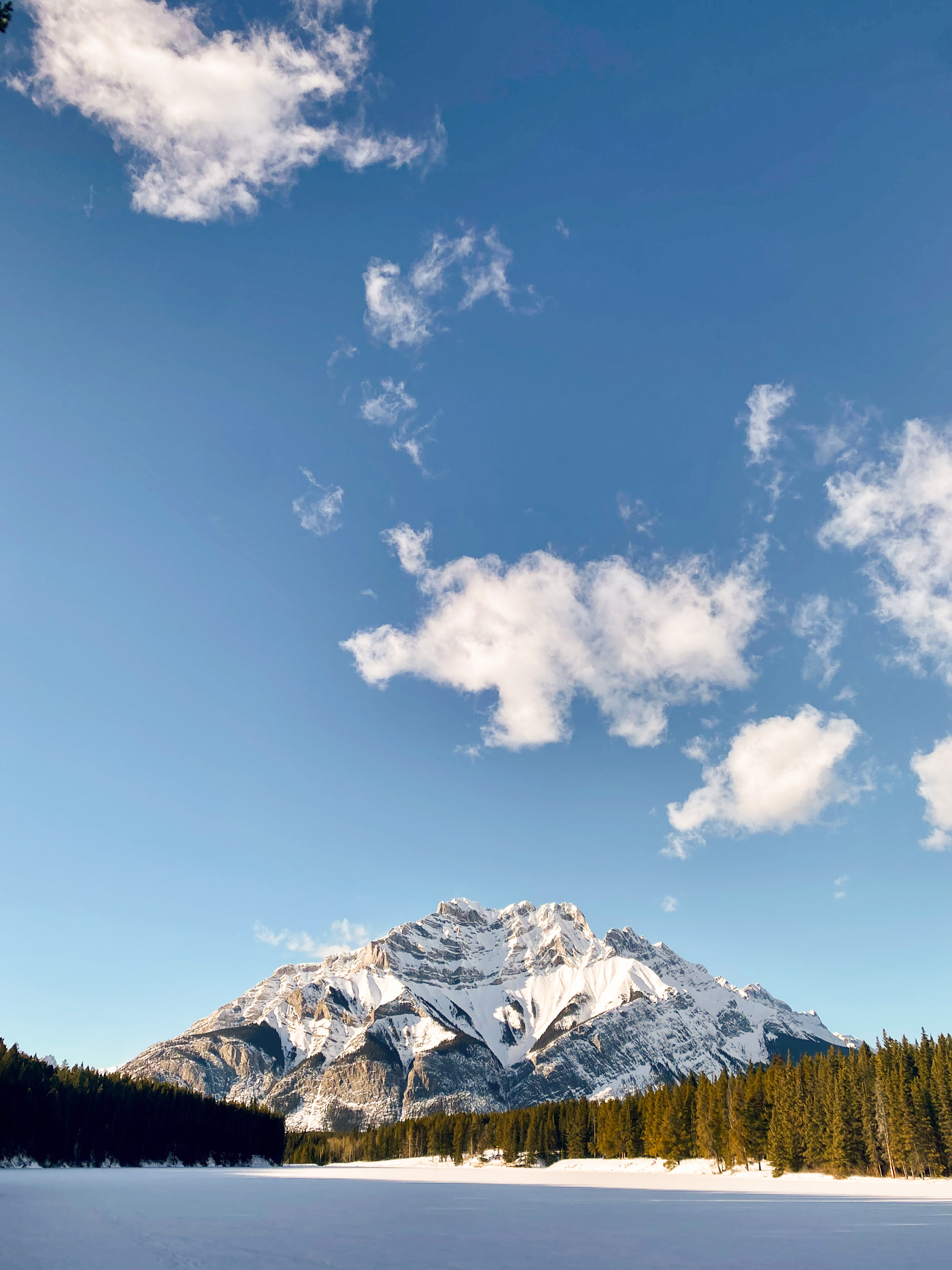 A snowy mountain overlooking a snow-covered lake