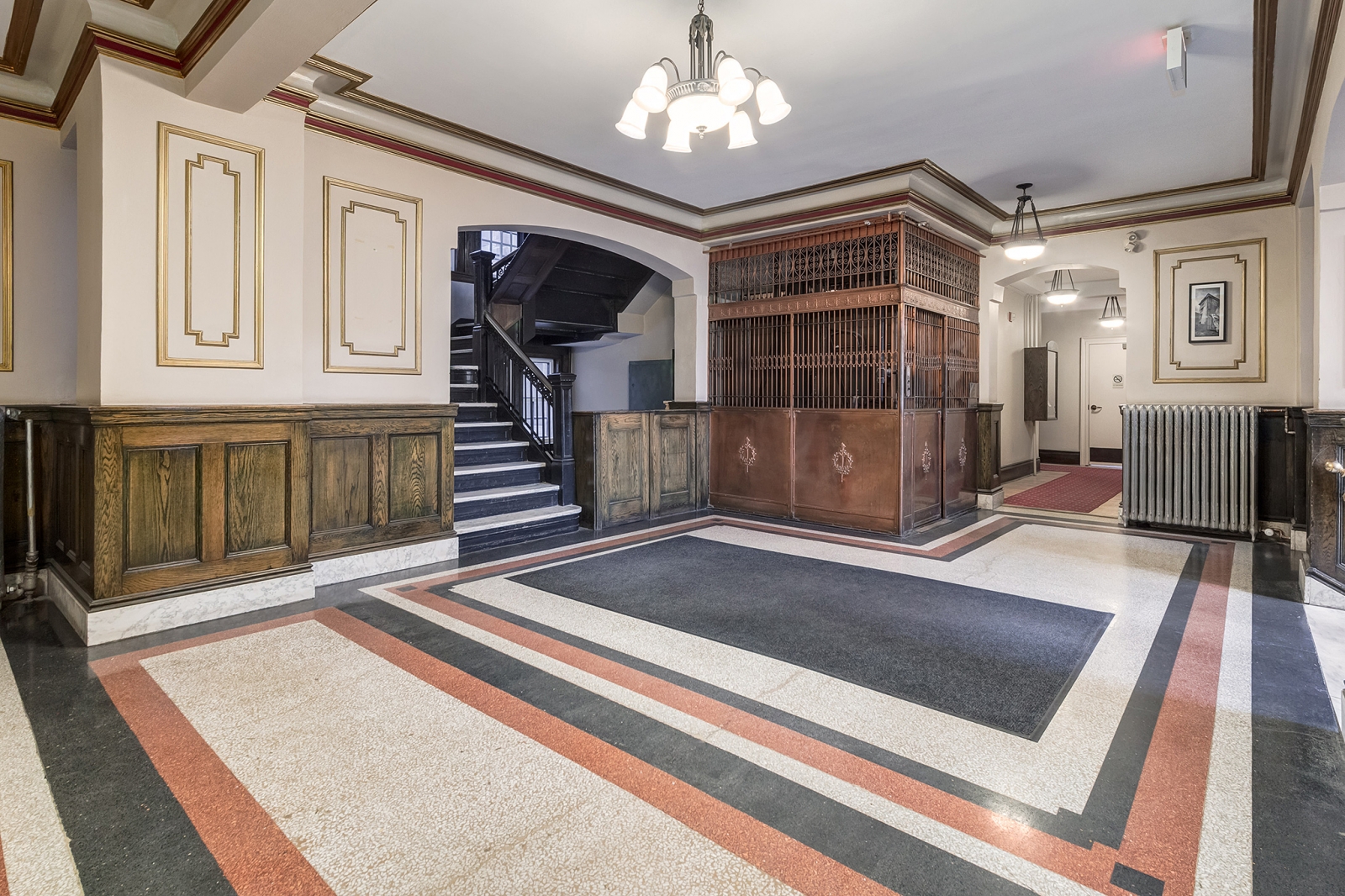 The elegant lobby includes a marble staircase and functional brass bird cage elevator.