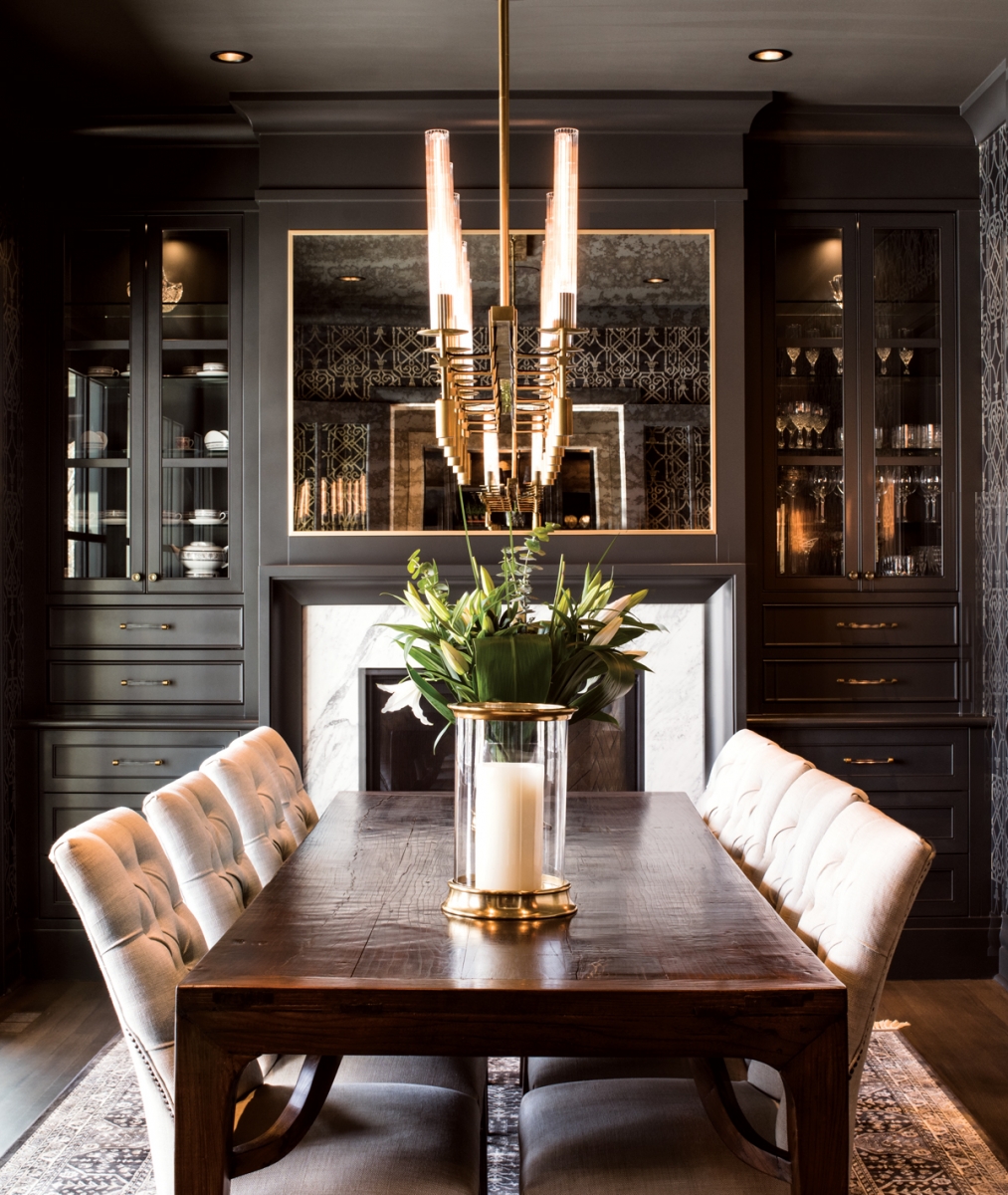 The dining room’s traditional details, such as the smoked-glass mirror over the fireplace and antique table from Hinchcliff & Lee create a sense of timeless elegance.