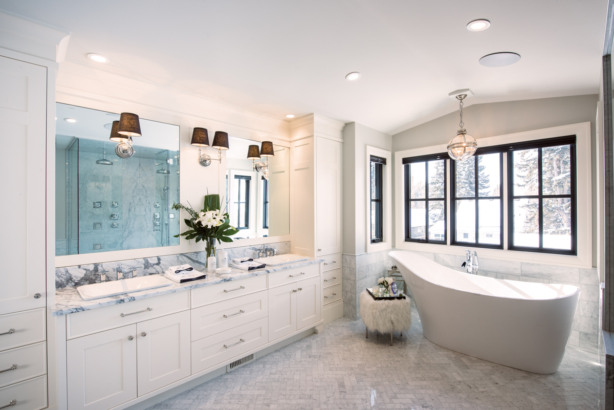 With its ample clean-lined vanity and herringbone-patterned Carrara-marble tile floor, the main ensuite is light and elegant with its oversized Aquabrass soaker tub and tufted stool. All electrical outlets are discreetly hidden within the cabinets. 