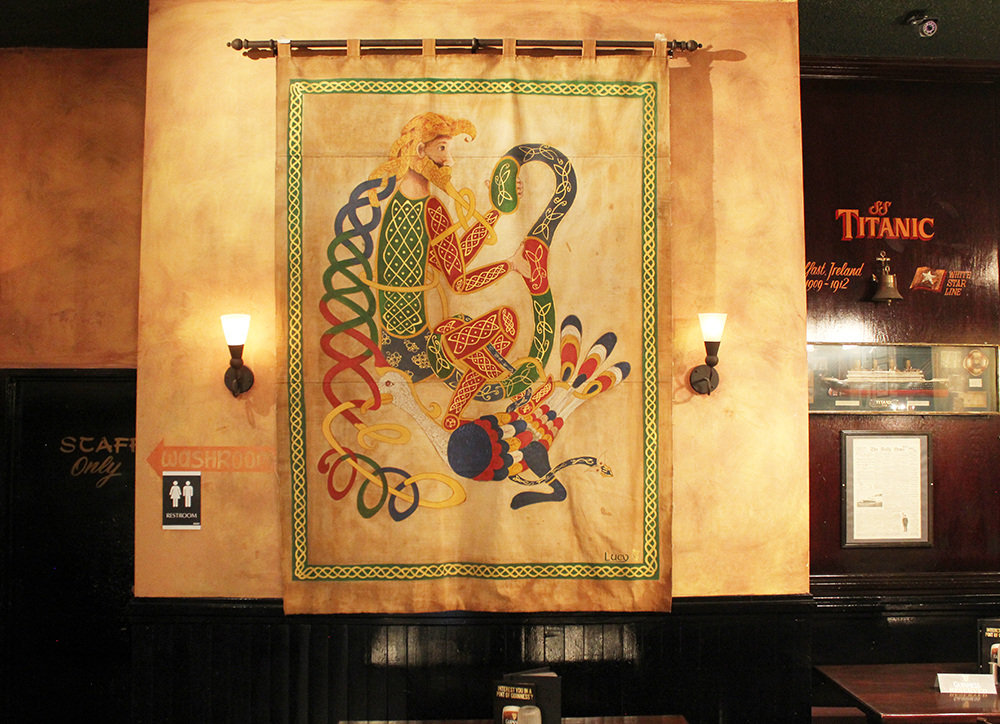 This and other tapestries hanging in the pub were created by a family friend from Ireland who now lives in Red Deer. She made them from old Boy Scout tents, coloured them with cold tea and fire and hand drew Celtic art from the Book of Kells, one of the world's oldest manuscripts held in Trinity University in Dublin. This tapestry is one of the illuminated letters from the Book of Kells.