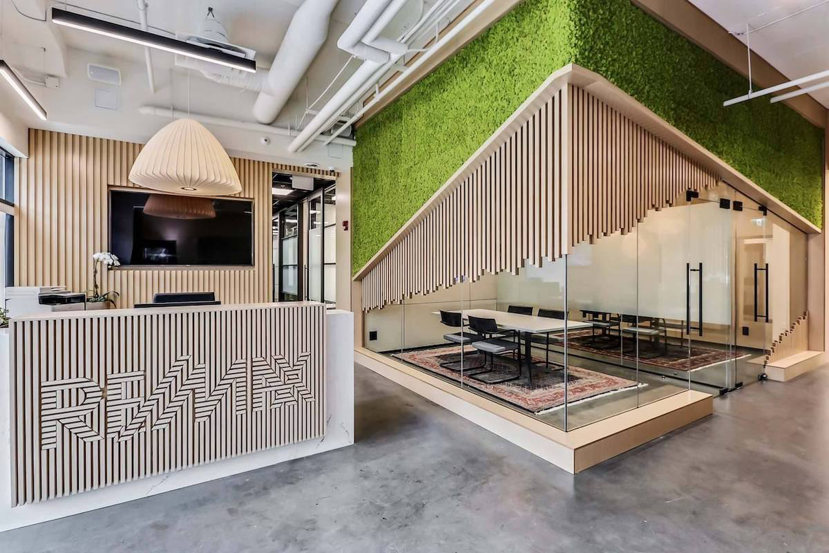 When you walk into the lobby of RE/MAX House of Real Estate, your eye is immediately drawn to the bright green moss wall. White oak slats partially cover the outside of meeting rooms and the reception area, subtly spelling out the company's name on the front desk.