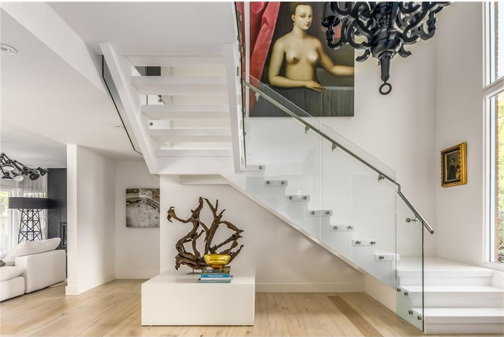 A matte black Moooi chandelier hangs over the glass staircase.