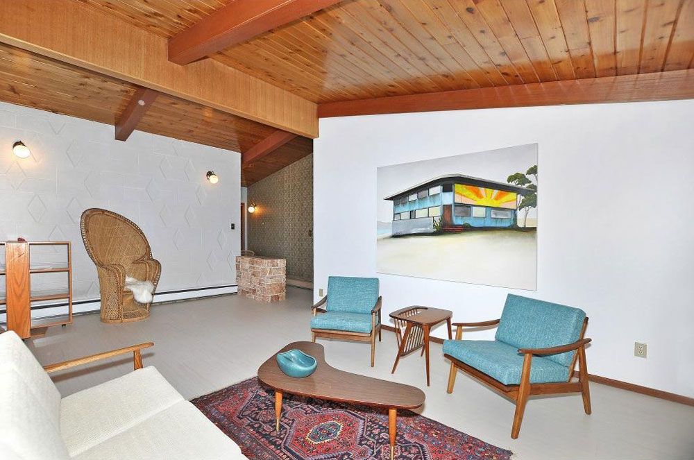 The living room has an original wood-paneled ceiling and cement feature wall, as well as new Marmoleum flooring.