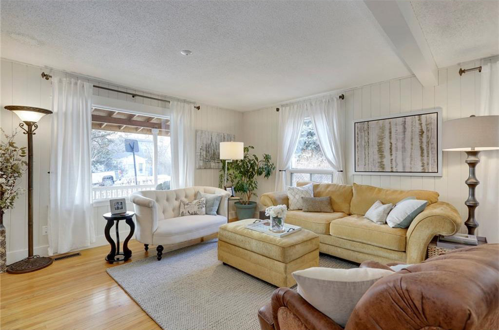 The living room has hardwood floors and white beadboard walls. 