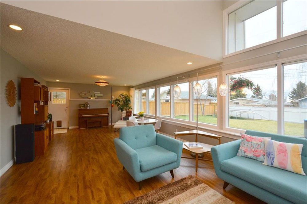 The living room has a wall of windows that overlook the backyard.